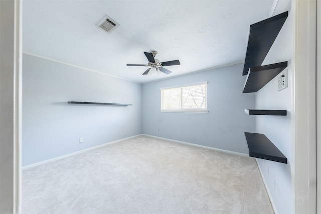 carpeted spare room featuring ceiling fan, visible vents, and baseboards