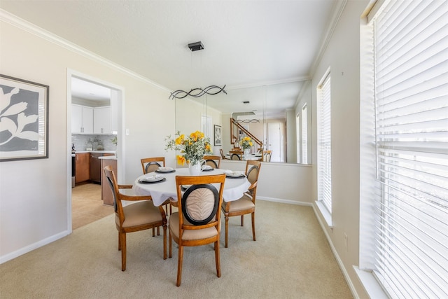 dining area featuring baseboards, ornamental molding, and light colored carpet