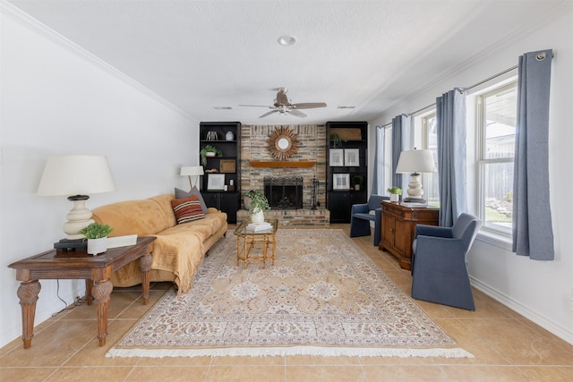 living room featuring a fireplace, crown molding, light tile patterned floors, a ceiling fan, and baseboards