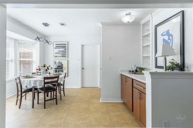 interior space featuring light countertops, visible vents, brown cabinetry, ornamental molding, and light tile patterned flooring