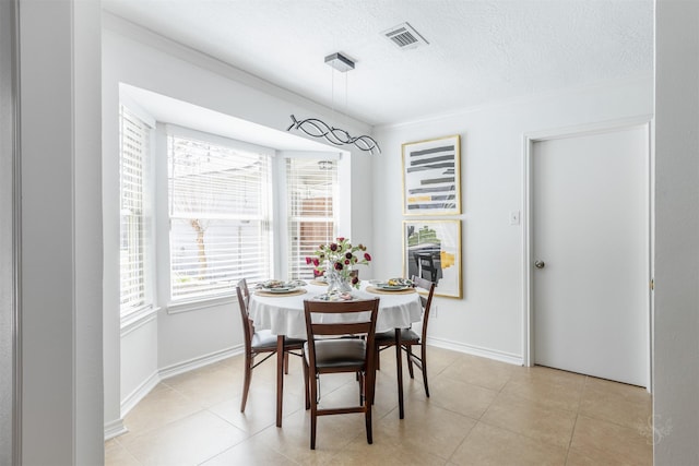 dining area featuring a textured ceiling, light tile patterned floors, and baseboards