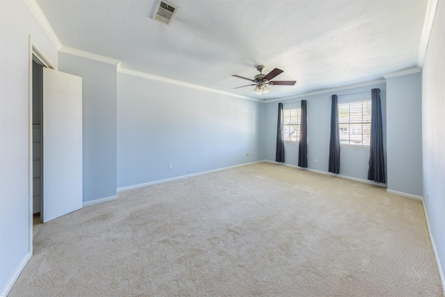 carpeted spare room featuring a textured ceiling, visible vents, a ceiling fan, baseboards, and ornamental molding