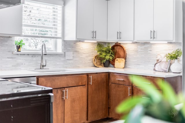 kitchen featuring light countertops, a sink, decorative backsplash, and white cabinetry