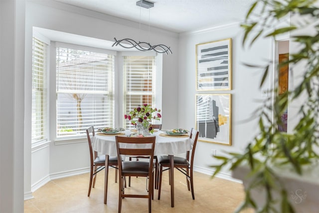 dining area featuring light tile patterned floors, ornamental molding, and baseboards