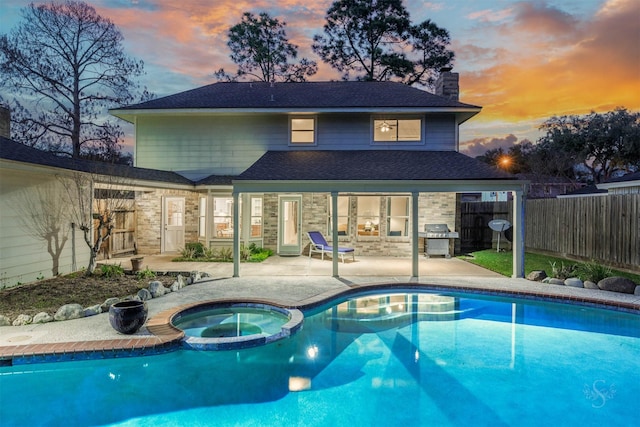 view of pool featuring a patio area, a pool with connected hot tub, fence, and area for grilling