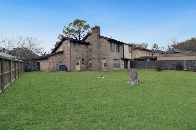 back of property featuring brick siding, a lawn, a chimney, and a fenced backyard