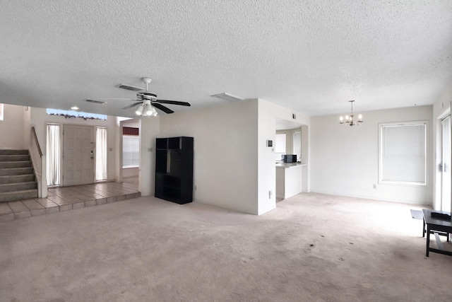 unfurnished living room with ceiling fan with notable chandelier, stairway, carpet, and a textured ceiling