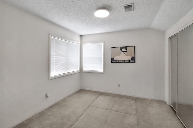 empty room with visible vents, carpet flooring, a textured ceiling, and lofted ceiling