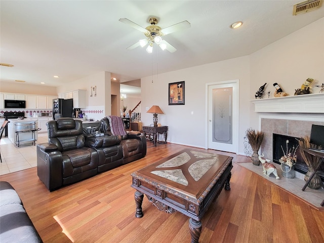 8002 Weeping Willow Pl, Missouri City, TX 77459 - living room featuring visible vents, stairs, light wood-style floors, and ceiling fan