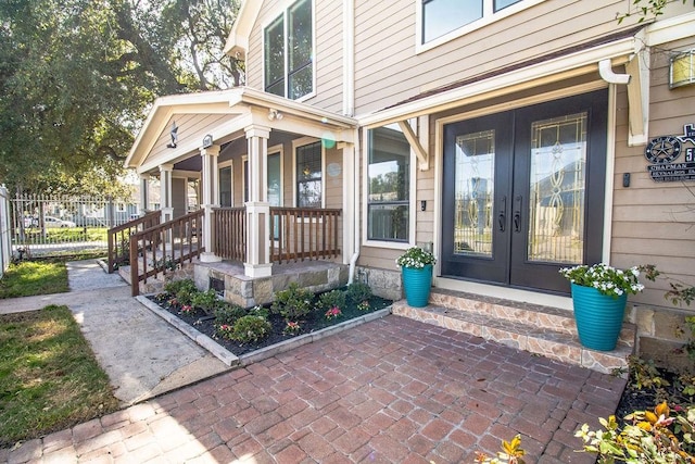 doorway to property with french doors, a porch, and fence