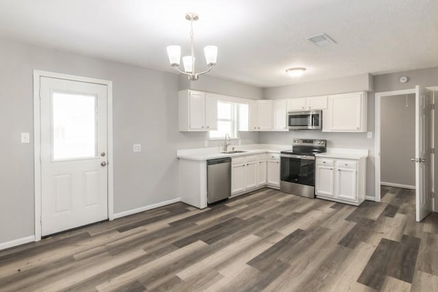 kitchen with light countertops, appliances with stainless steel finishes, dark wood-style floors, white cabinets, and a sink