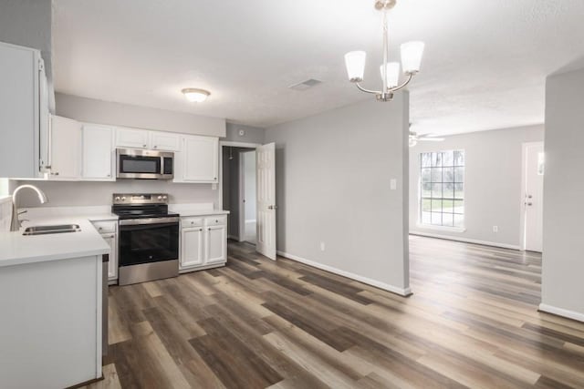 kitchen with dark wood-type flooring, light countertops, white cabinets, stainless steel appliances, and a sink