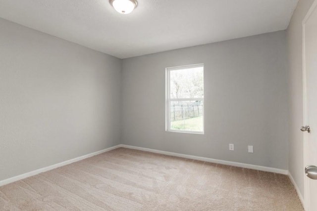 empty room featuring baseboards and light colored carpet