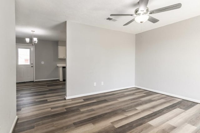 interior space with dark wood finished floors, visible vents, ceiling fan with notable chandelier, and baseboards