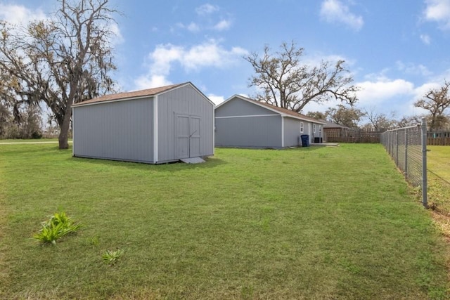 view of yard featuring a storage unit, an outbuilding, and fence