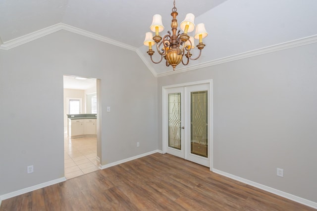 spare room featuring lofted ceiling, baseboards, wood finished floors, and french doors