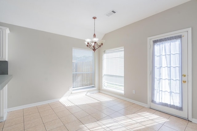 unfurnished dining area featuring light tile patterned floors, a chandelier, lofted ceiling, visible vents, and baseboards