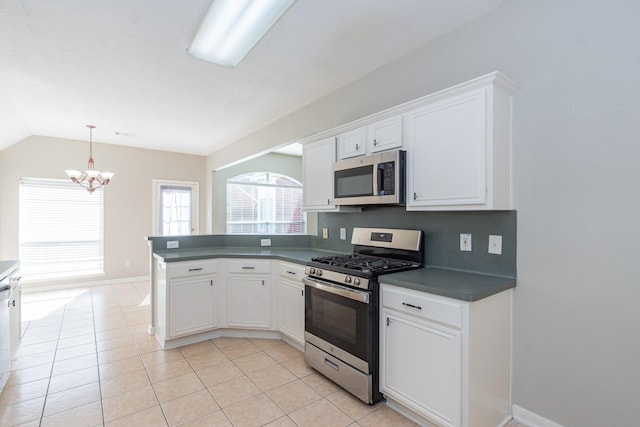 kitchen featuring light tile patterned floors, white cabinets, dark countertops, appliances with stainless steel finishes, and a peninsula