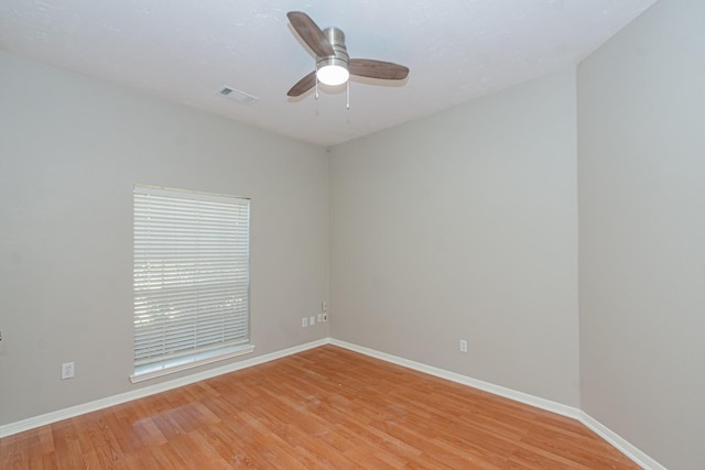 spare room with light wood-type flooring, baseboards, visible vents, and ceiling fan