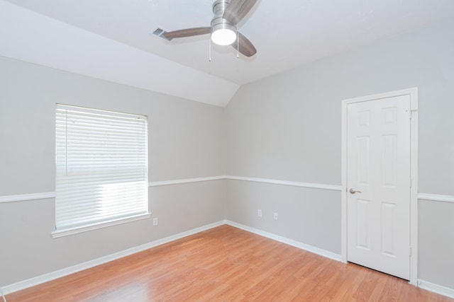 spare room with vaulted ceiling, ceiling fan, light wood finished floors, and baseboards