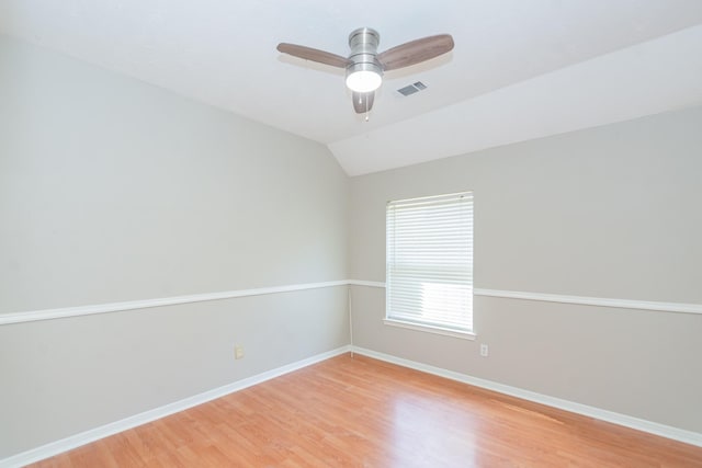 empty room with baseboards, visible vents, a ceiling fan, lofted ceiling, and light wood-style floors