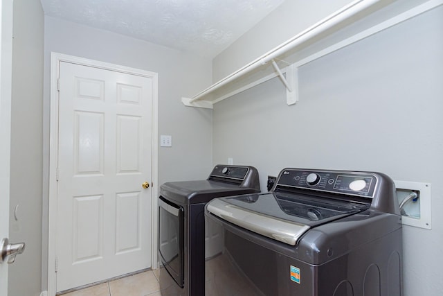 clothes washing area featuring laundry area, washing machine and clothes dryer, and light tile patterned floors