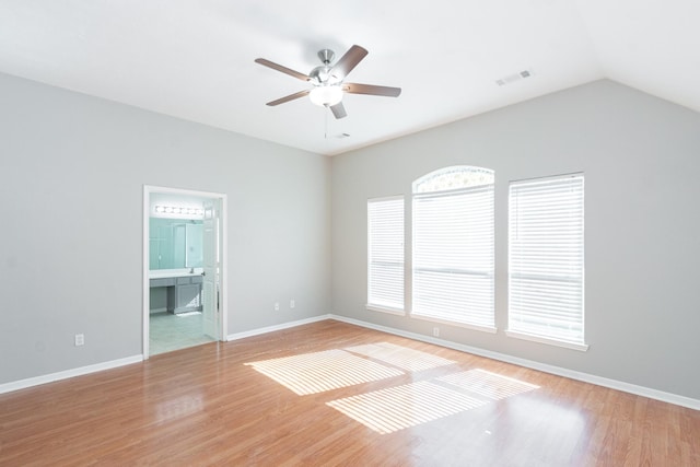 spare room featuring lofted ceiling, wood finished floors, a ceiling fan, visible vents, and baseboards