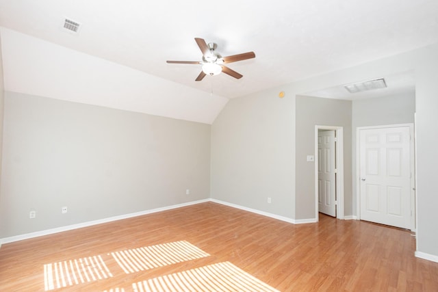 interior space with visible vents, light wood-style floors, a ceiling fan, vaulted ceiling, and baseboards