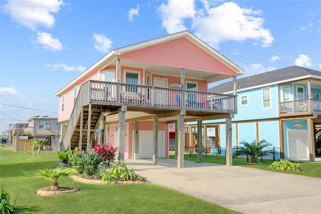 raised beach house with covered porch, concrete driveway, a garage, a front yard, and a carport