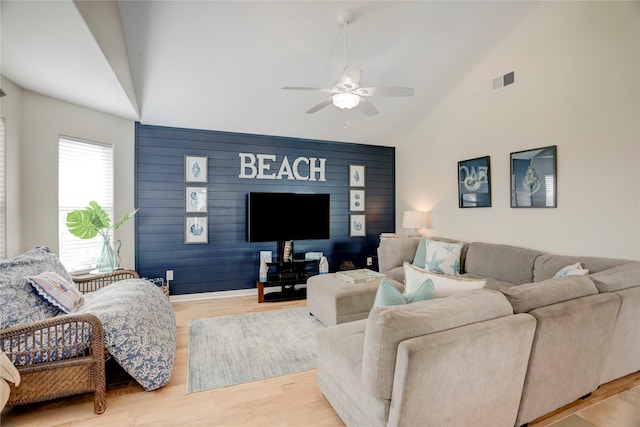 living area featuring a ceiling fan, visible vents, high vaulted ceiling, and wood finished floors