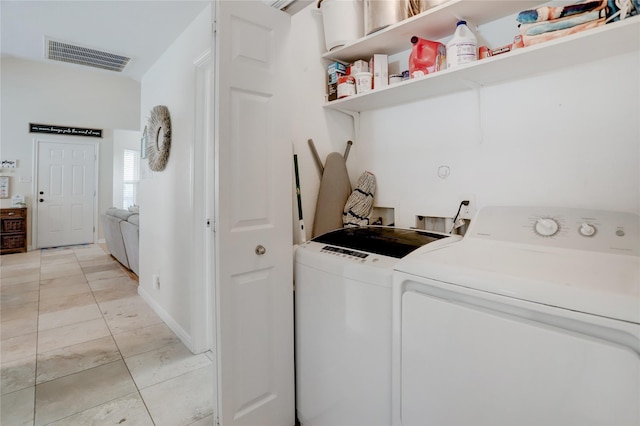 laundry area with washer and clothes dryer, light tile patterned floors, visible vents, laundry area, and baseboards