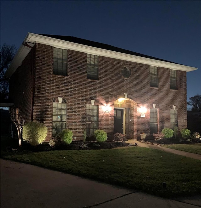 view of front of home with brick siding and a lawn