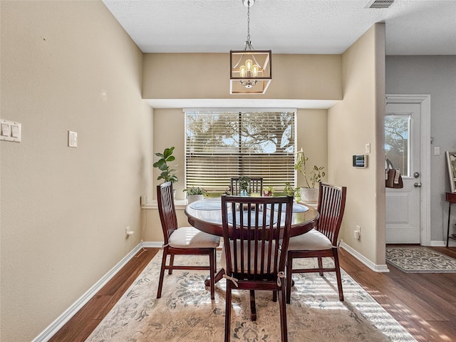 dining room featuring a chandelier, baseboards, and dark wood-style flooring