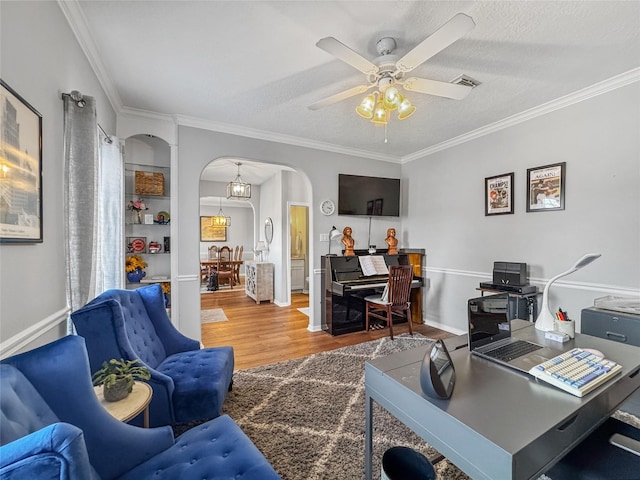 office space with visible vents, wood finished floors, arched walkways, crown molding, and ceiling fan