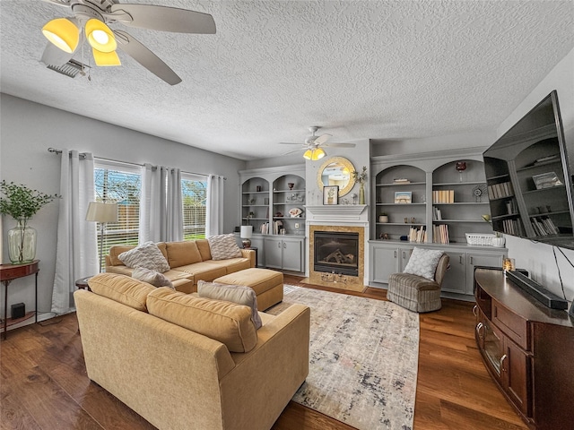 living room with a tiled fireplace, wood finished floors, visible vents, and a textured ceiling