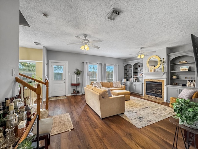 living area featuring visible vents, plenty of natural light, a fireplace, and hardwood / wood-style flooring