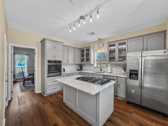 kitchen featuring dark wood-style flooring, gray cabinetry, stainless steel appliances, and a sink