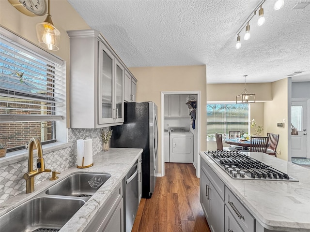 kitchen featuring washing machine and clothes dryer, gray cabinetry, dark wood-style floors, stainless steel appliances, and a sink