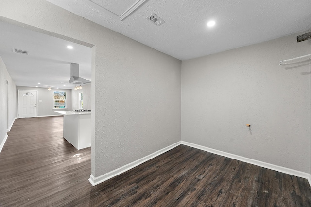 spare room with dark wood-style flooring, visible vents, and baseboards