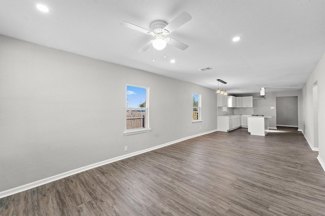 unfurnished living room featuring dark wood finished floors, baseboards, and ceiling fan