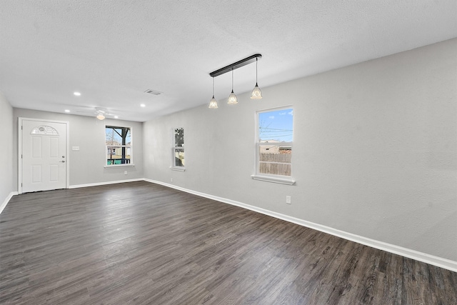 interior space with a textured ceiling, dark wood-style flooring, visible vents, and baseboards