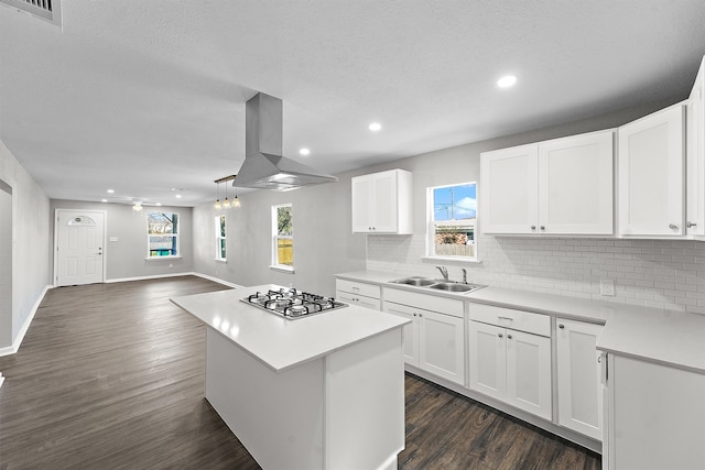 kitchen with island exhaust hood, dark wood-type flooring, a sink, and stainless steel gas stovetop