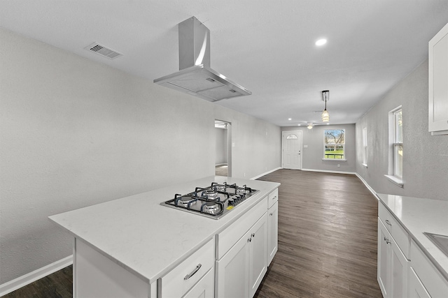 kitchen featuring stainless steel gas cooktop, dark wood-type flooring, exhaust hood, visible vents, and white cabinets