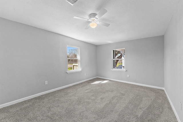 carpeted empty room featuring ceiling fan, a textured wall, a textured ceiling, and baseboards