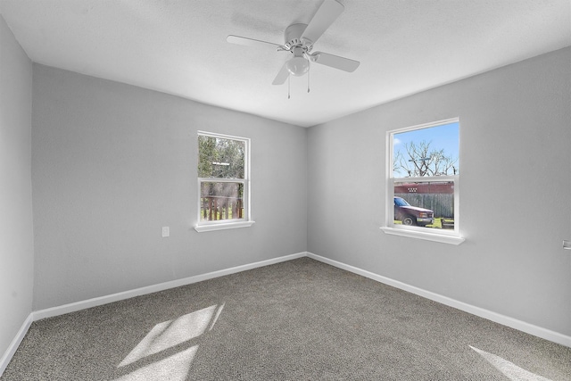 carpeted empty room featuring a textured ceiling, a ceiling fan, and baseboards