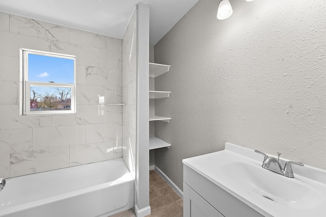 full bath with a textured wall,  shower combination, vanity, and baseboards