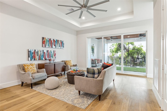 sitting room featuring light wood-style floors, ceiling fan, visible vents, and a raised ceiling