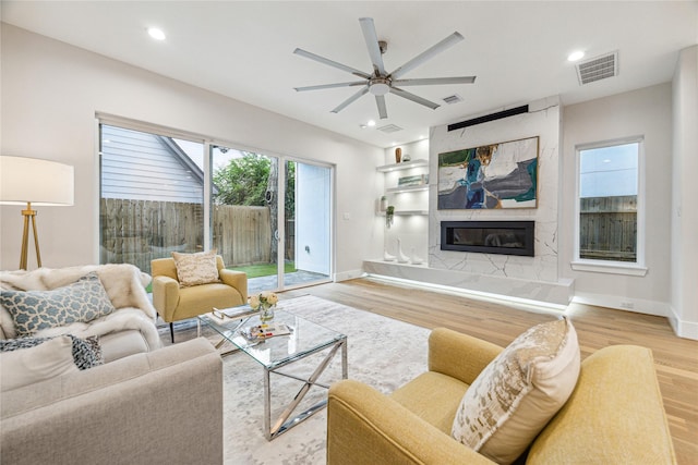 living area with recessed lighting, visible vents, a tiled fireplace, and wood finished floors