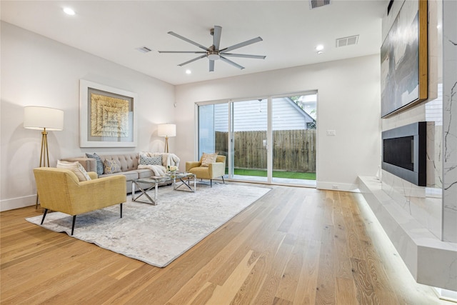 living area with light wood-type flooring, a tile fireplace, visible vents, and recessed lighting