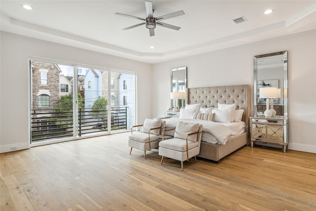 bedroom with light wood finished floors, baseboards, visible vents, a raised ceiling, and access to exterior